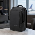 NOMATIC 20L Travel Pack in Black standing in an airport business-travel setting