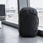 Peak Design Travel Backpack 45L in Black standing beside an airport terminal window