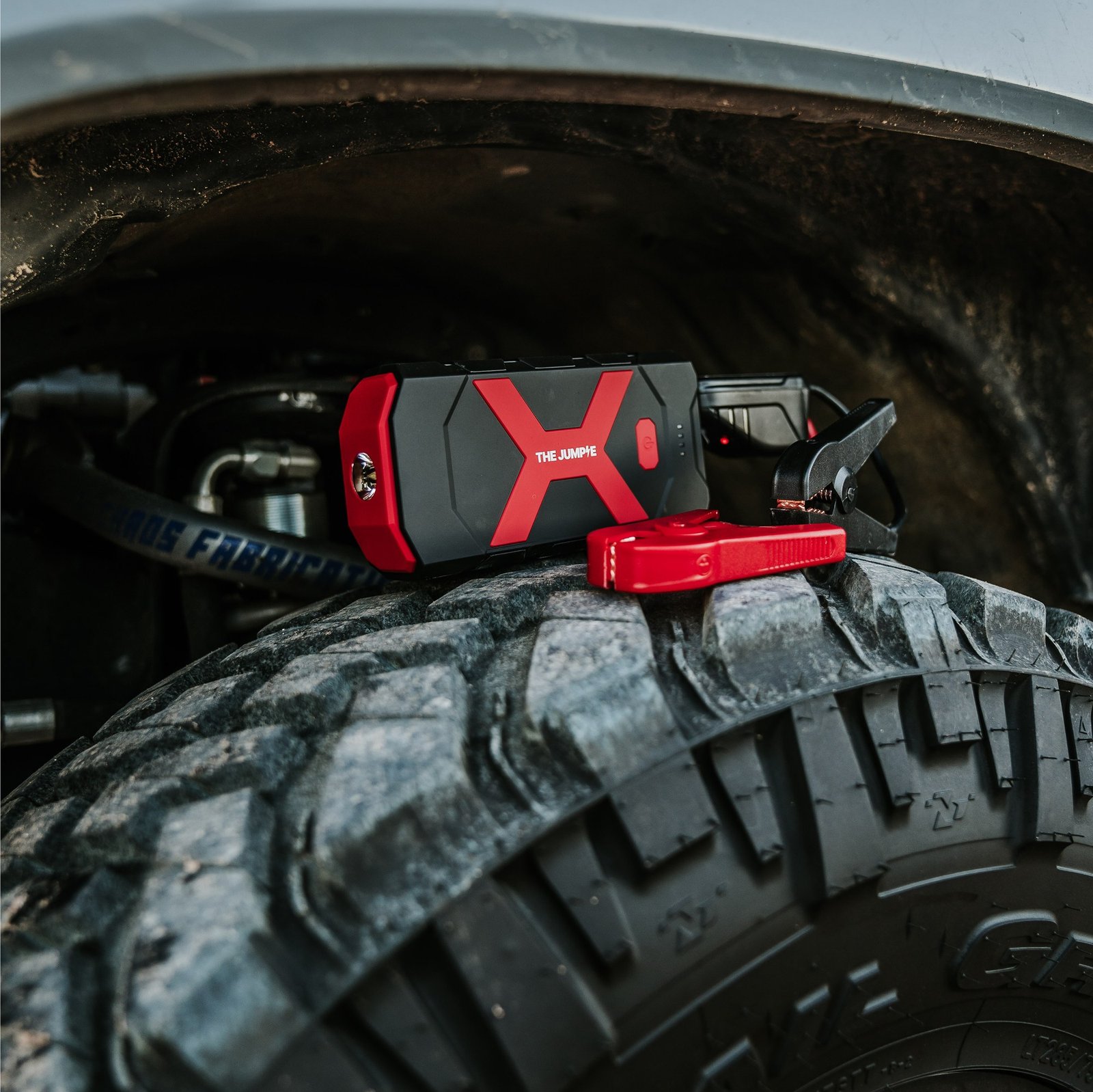Redi Jumpie jump starter and clamps resting on a vehicle tire