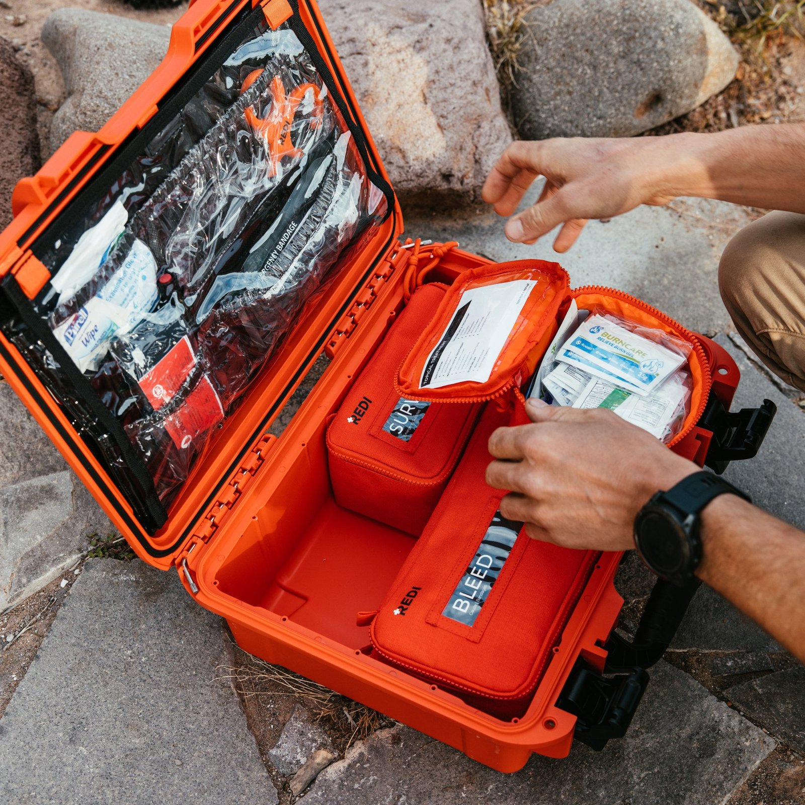 Hands opening labeled pouches inside a Redi Roadie Pro+ hard case